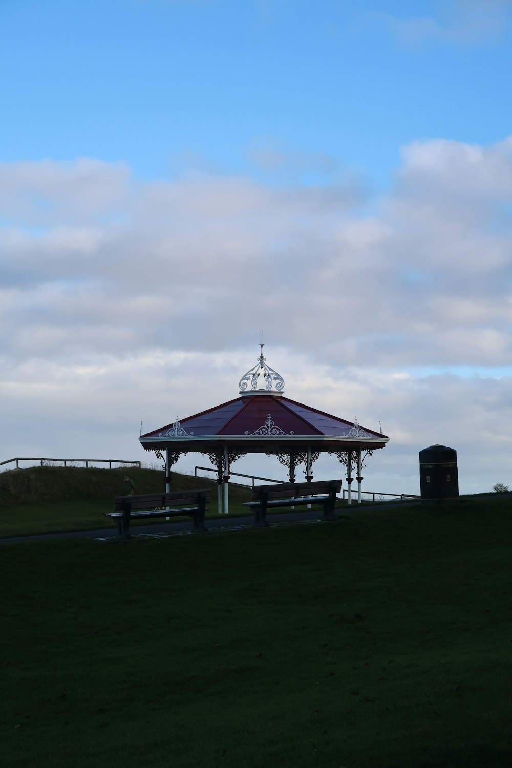a red and white gazebo sitting on top of a lush green field