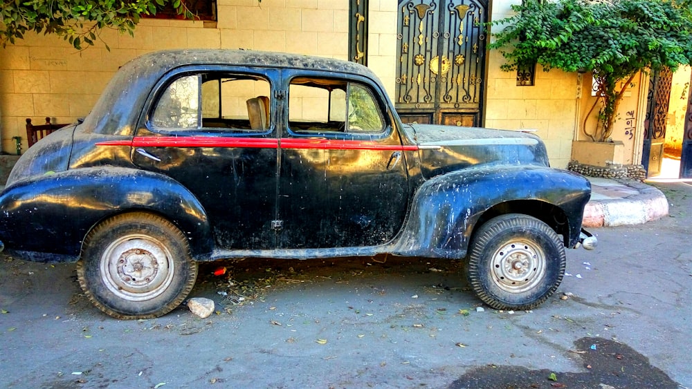 an old black car parked in front of a building