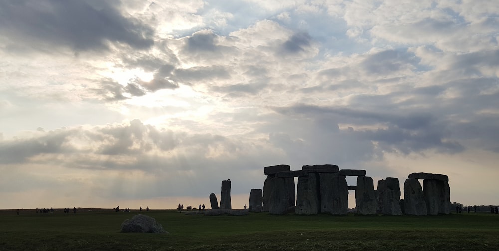 a large stonehenge standing in a field under a cloudy sky