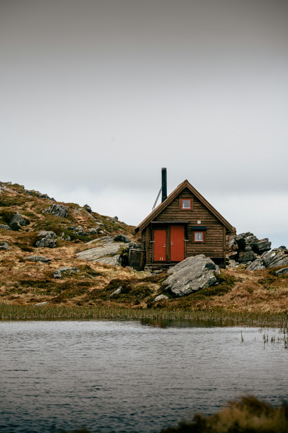 a small cabin sitting on top of a hill next to a body of water