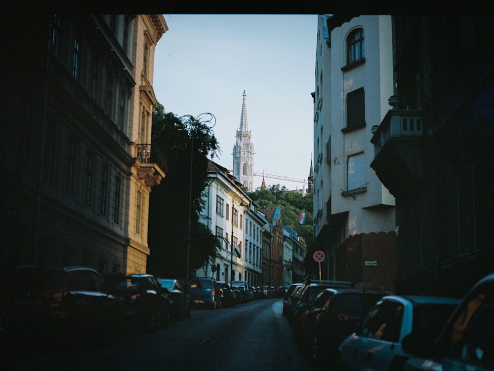 a city street lined with parked cars and tall buildings