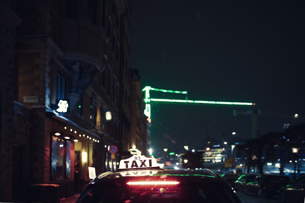 a taxi cab driving down a city street at night