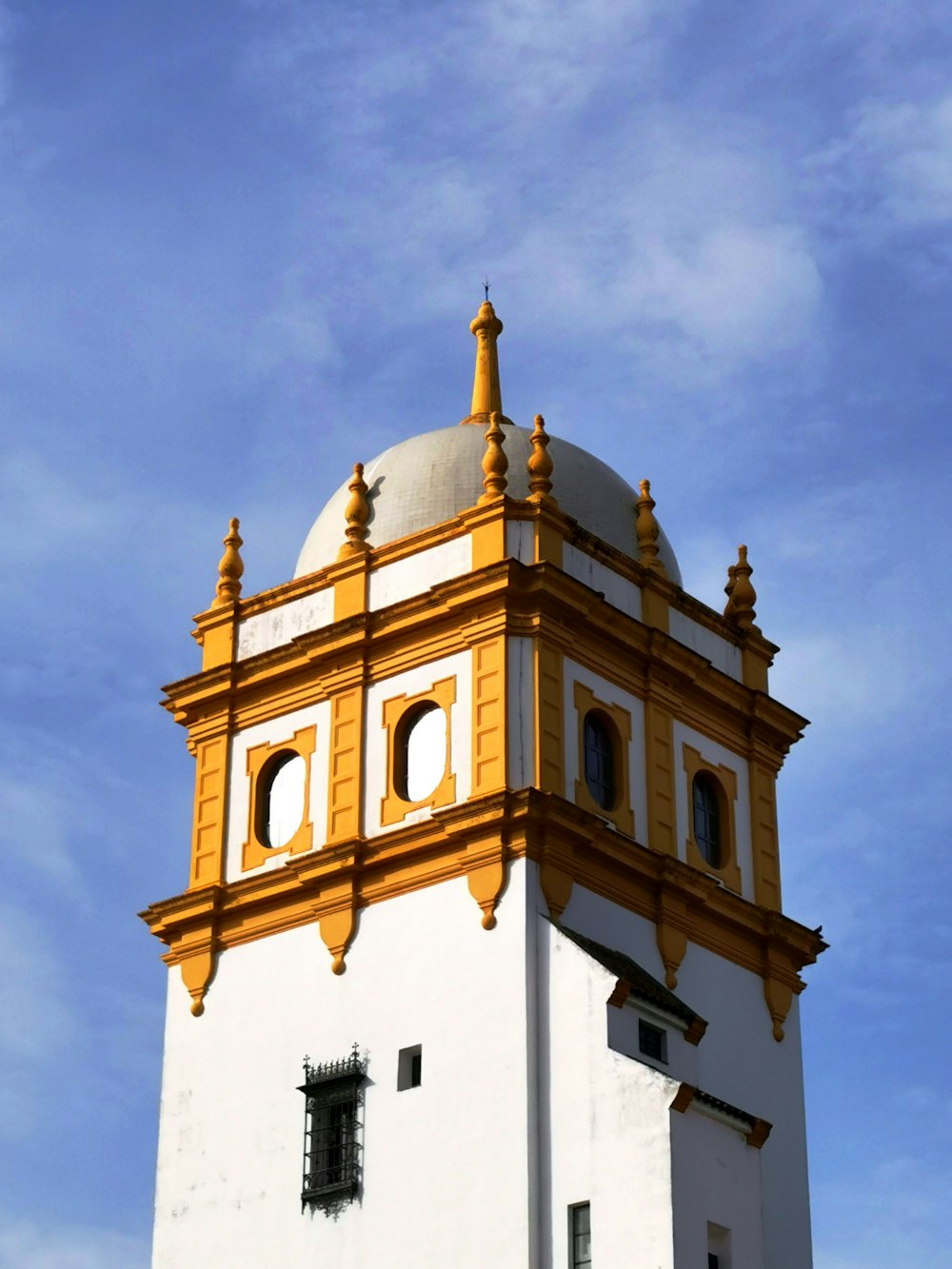 a tall white and yellow building with a clock on it's side