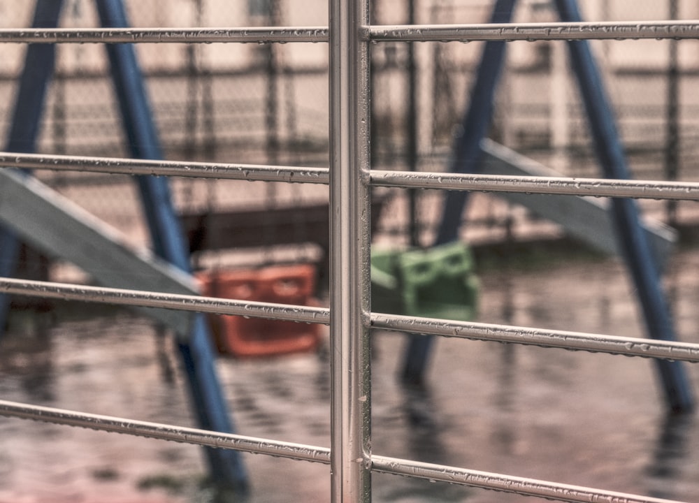 a metal fence with a slide in the background