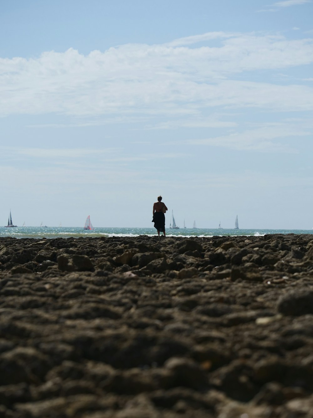 a man standing on top of a sandy beach next to the ocean