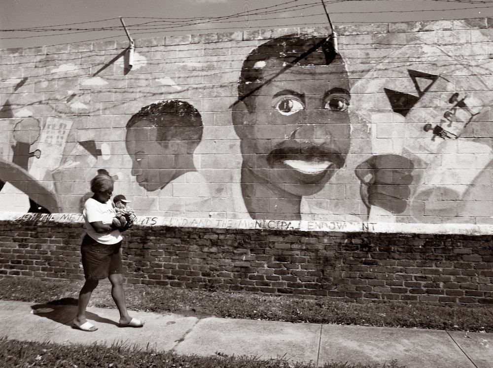 A woman and baby pass a neighborhood mural in New Orleans
