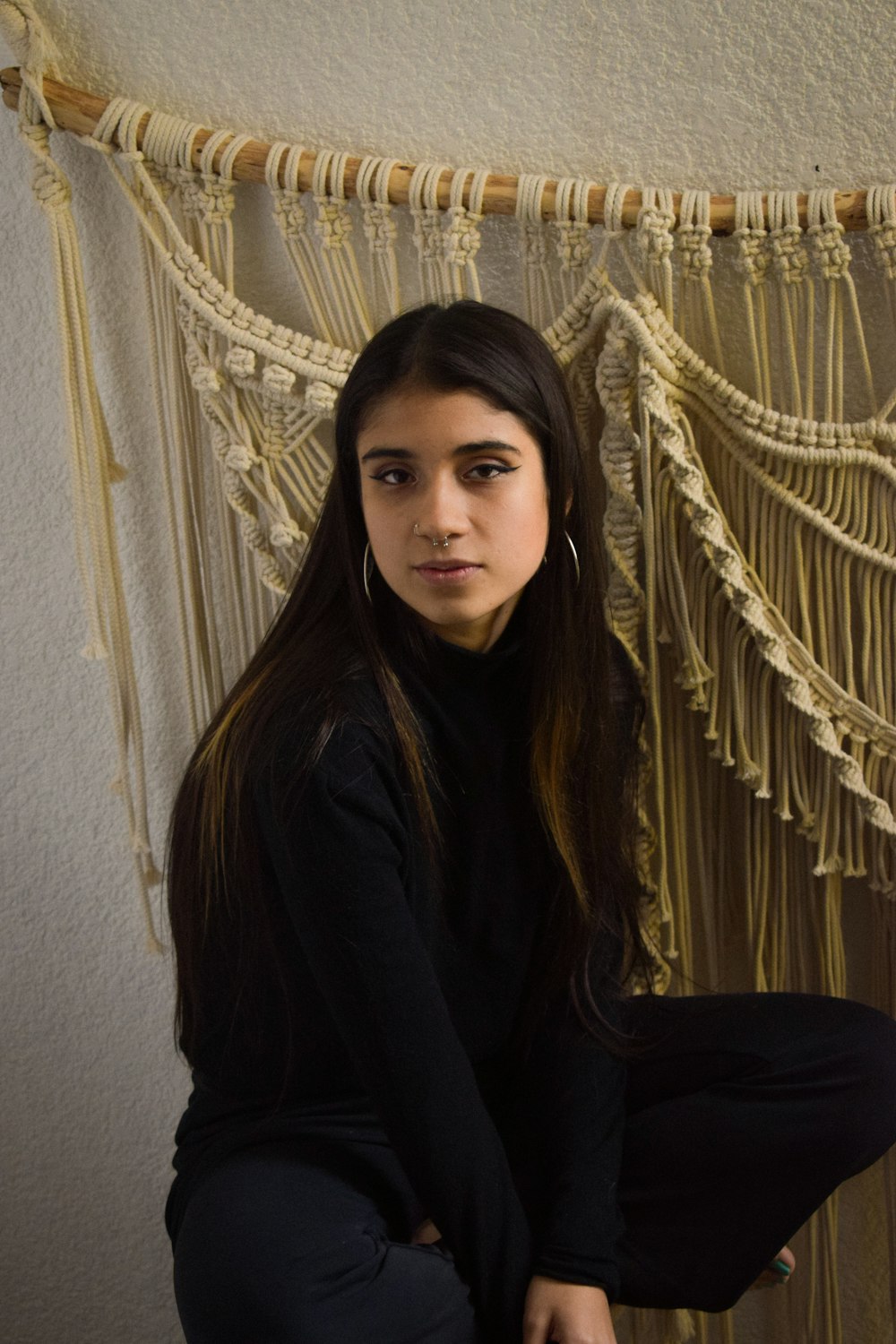 a woman sitting on the floor in front of a macrame