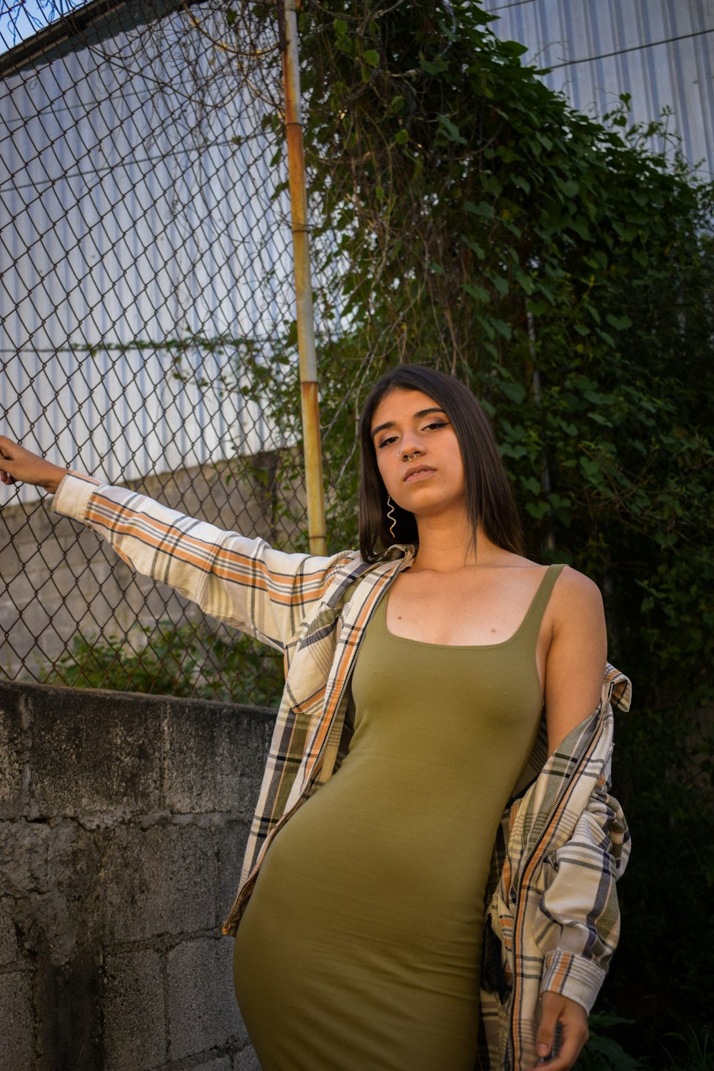 uma mulher em um vestido verde encostado em uma cerca