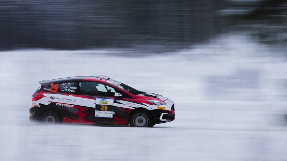 a red and white car driving through the snow