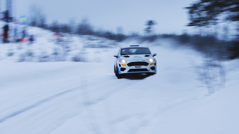 a white car driving down a snow covered road