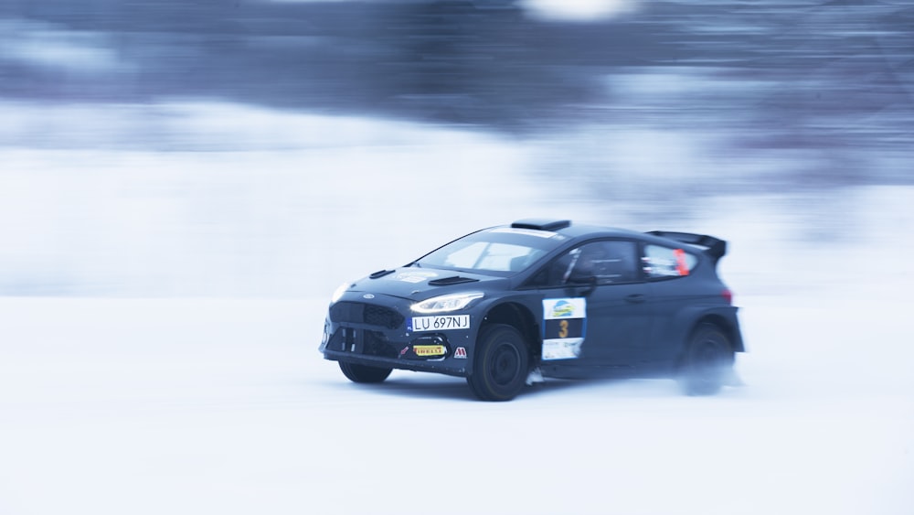 a car driving on a snowy road with trees in the background