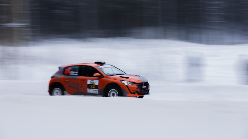 a red car driving through a snow covered field