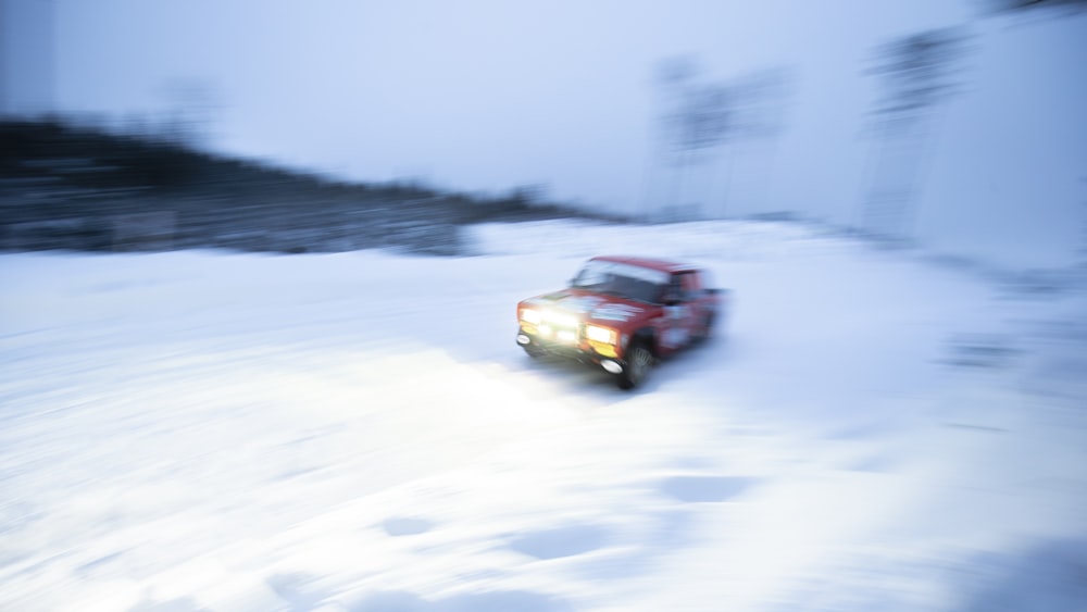 a red truck driving down a snow covered road