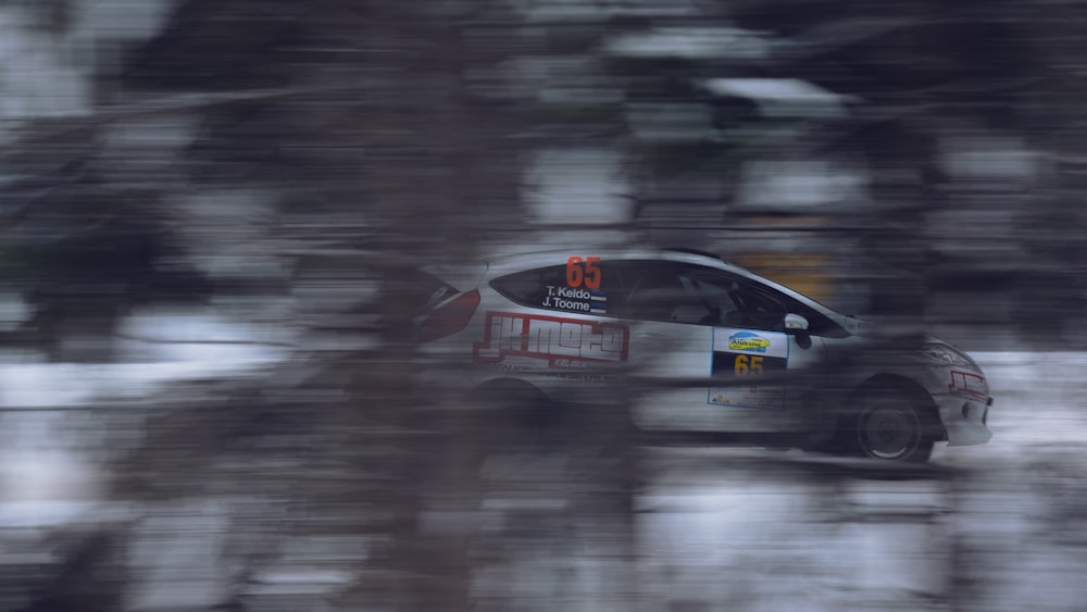 a car driving on a snowy road with trees in the background