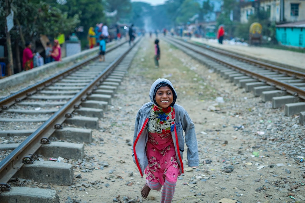a little girl walking down a train track