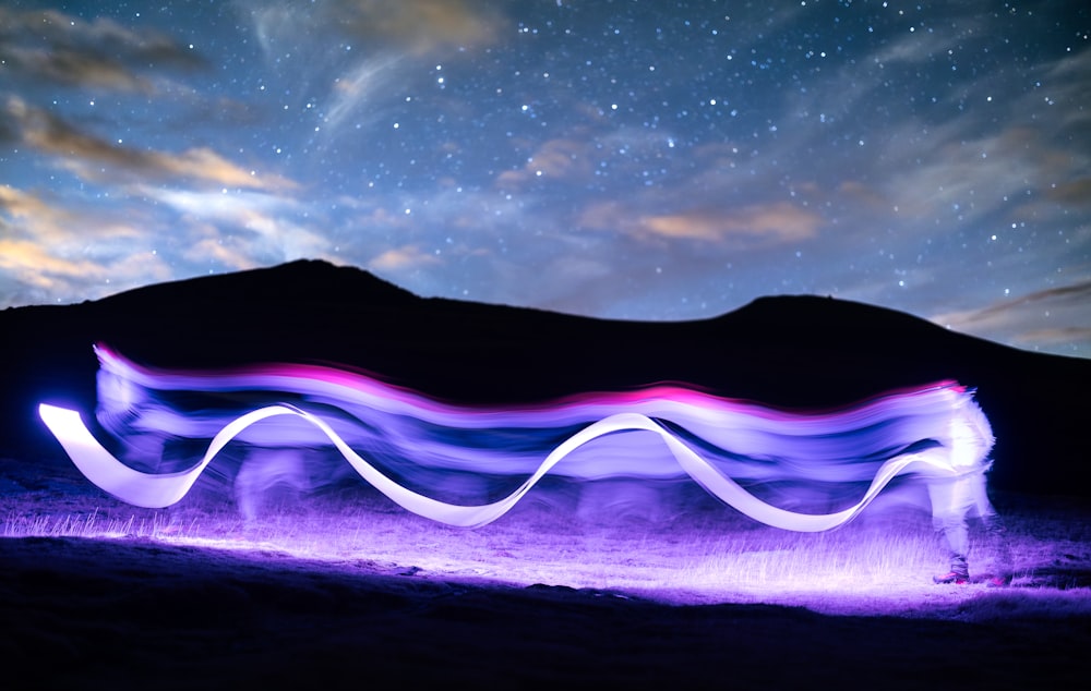 a long exposure photo of a wave in the night sky