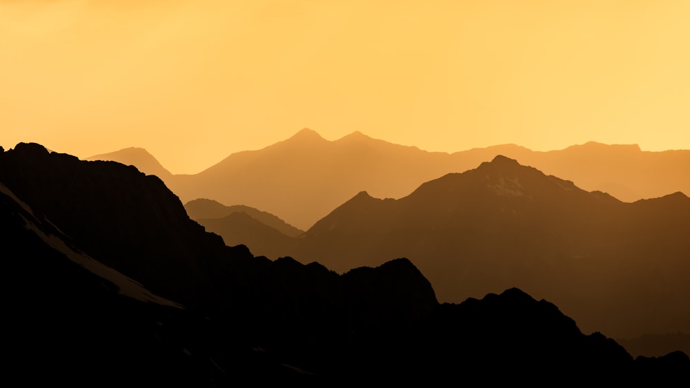 a bird flying over a mountain range at sunset