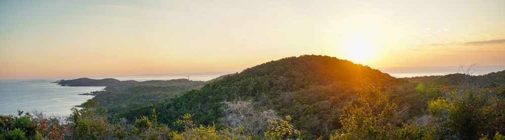 the sun is setting over a mountain with a body of water in the background