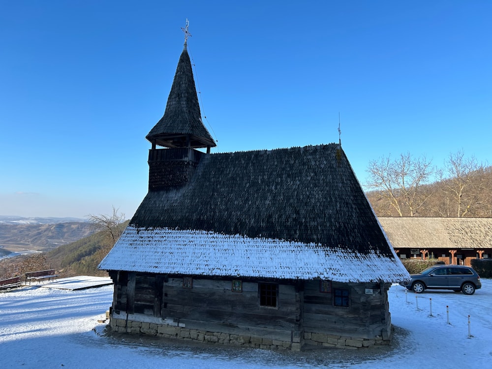 a small wooden church with a steeple and a snow covered roof