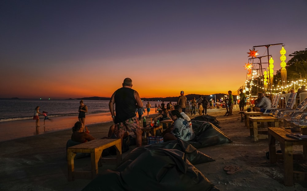 a group of people sitting on top of a sandy beach