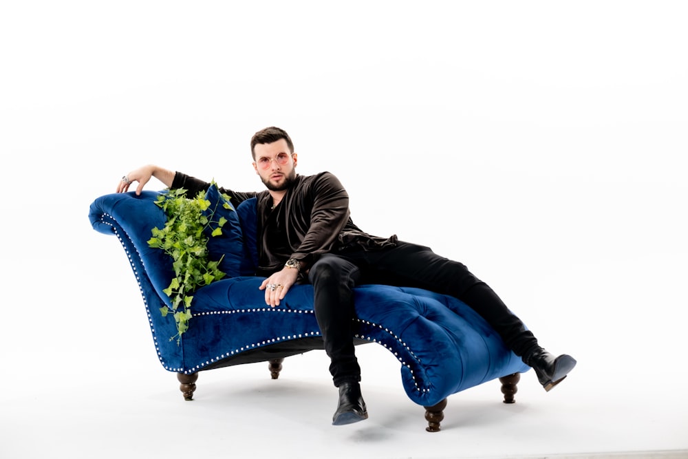 a man sitting on a blue couch with a plant on it