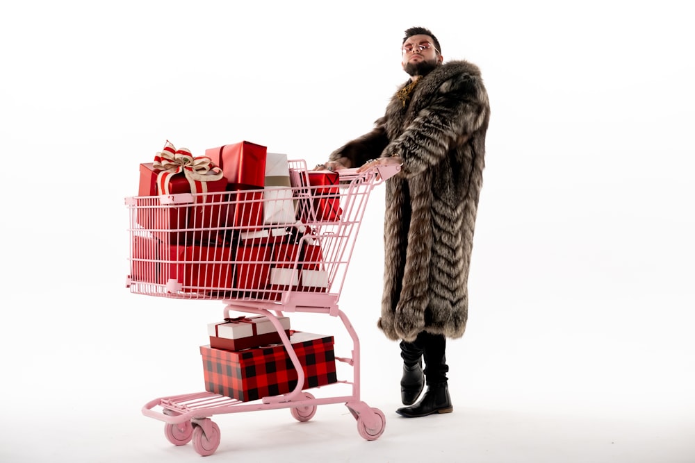 a man in a fur coat pushing a shopping cart filled with presents