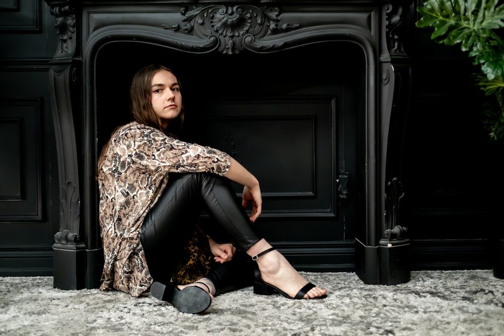 a woman sitting on the floor in front of a fireplace