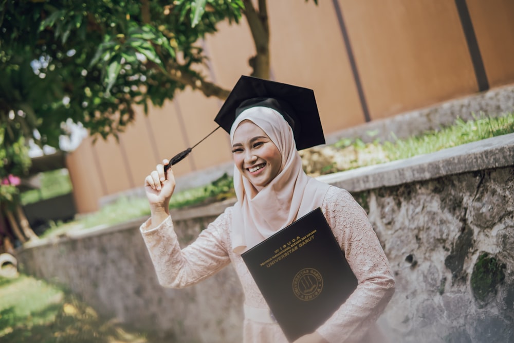 a woman in a graduation gown holding a book