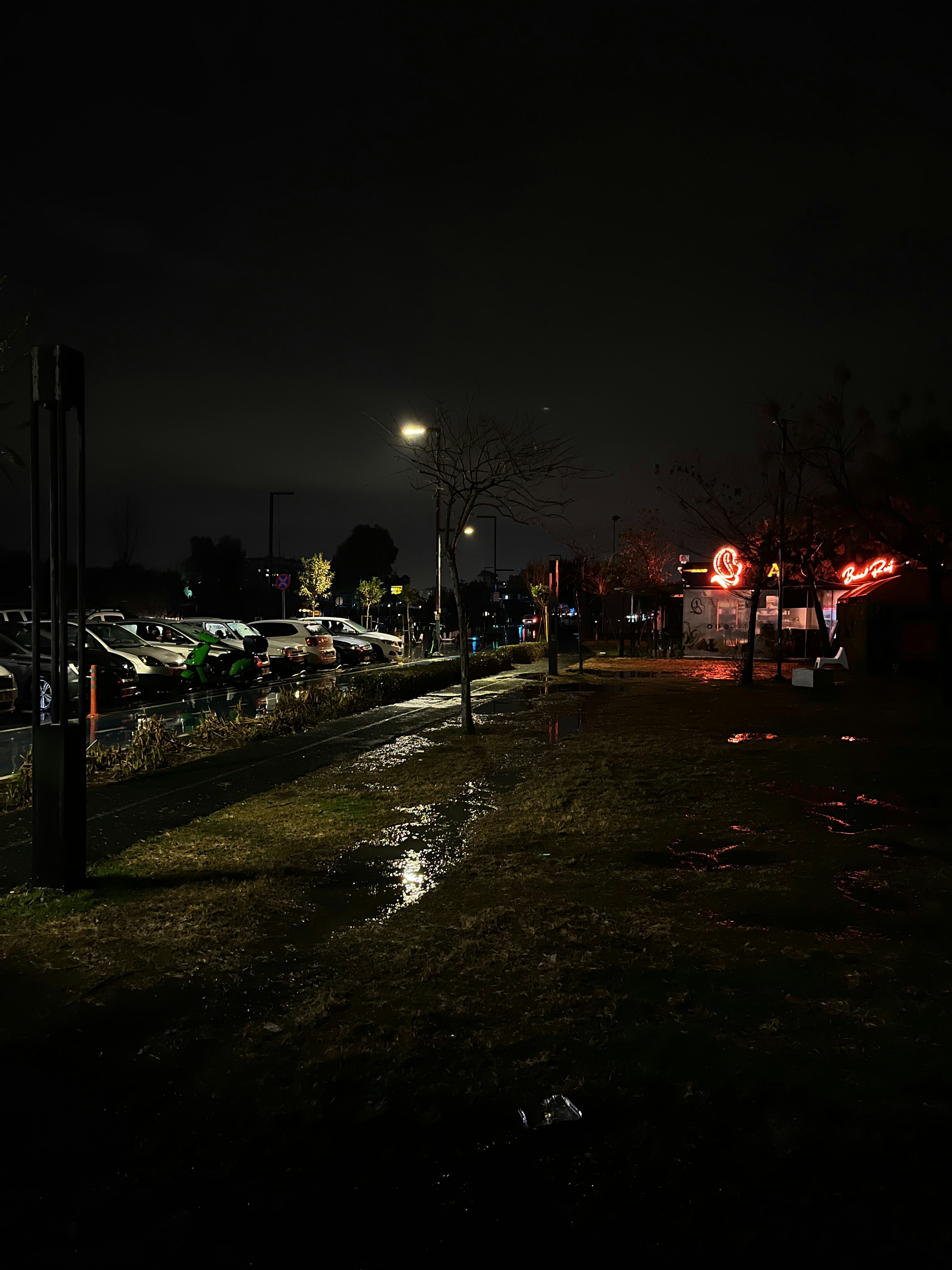 a street at night with cars parked on the side of the road