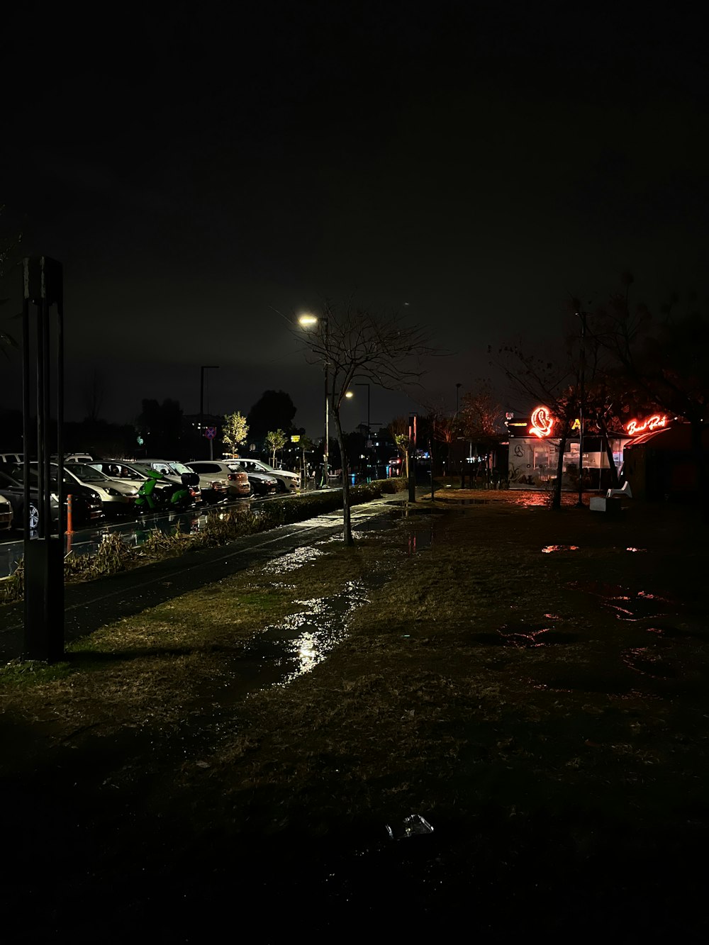 a street at night with cars parked on the side of the road