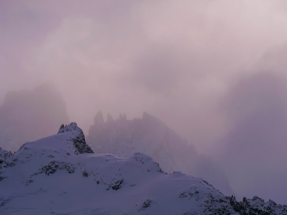 a mountain covered in snow and clouds on a cloudy day