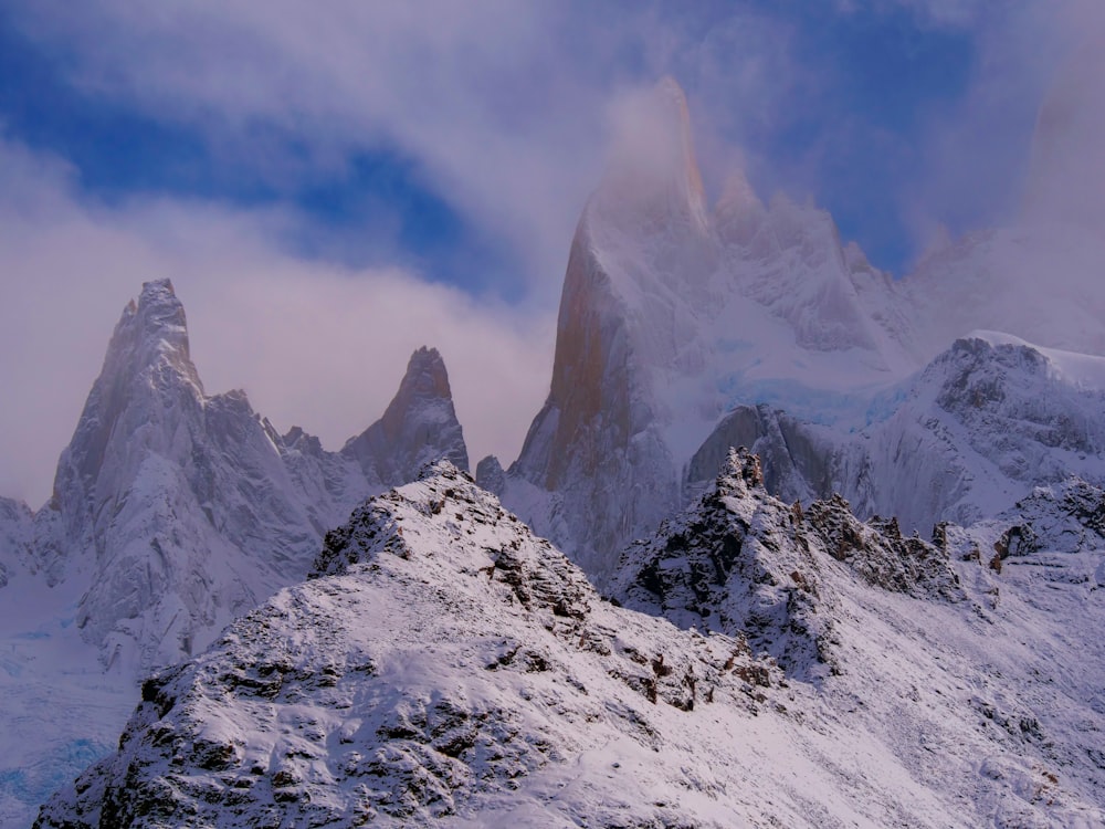 a mountain range covered in snow under a cloudy sky