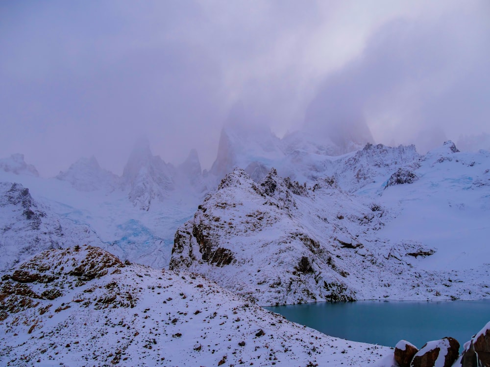 una cadena montañosa cubierta de nieve con un lago en primer plano