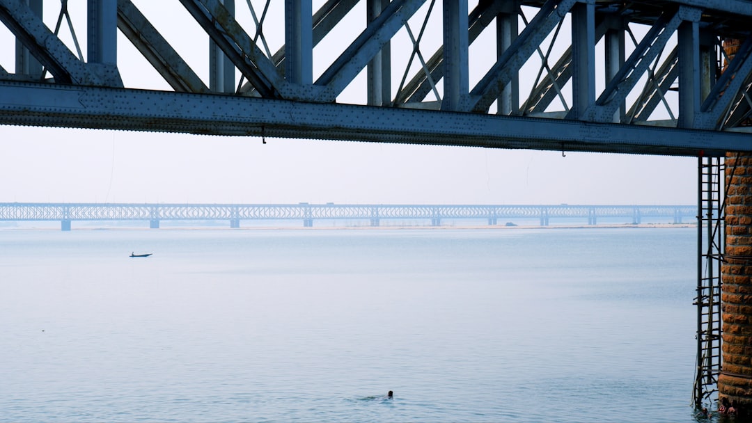 a person swimming in a body of water under a bridge, Swimming below Rajahmundry Havelock Bridge on River Godavari.