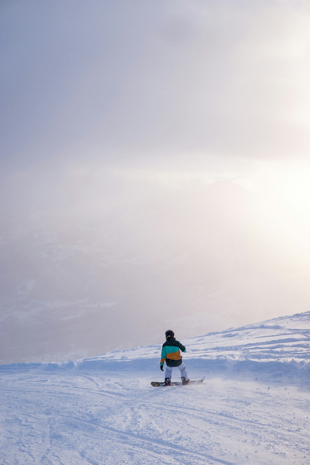 a person riding a snowboard down a snow covered slope