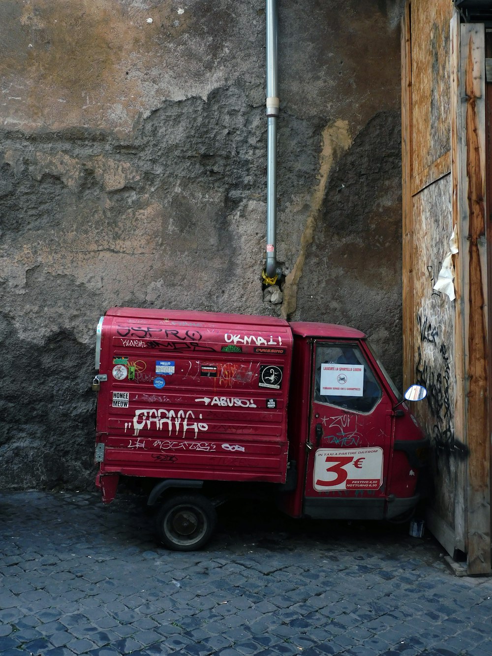 a small red truck parked next to a building