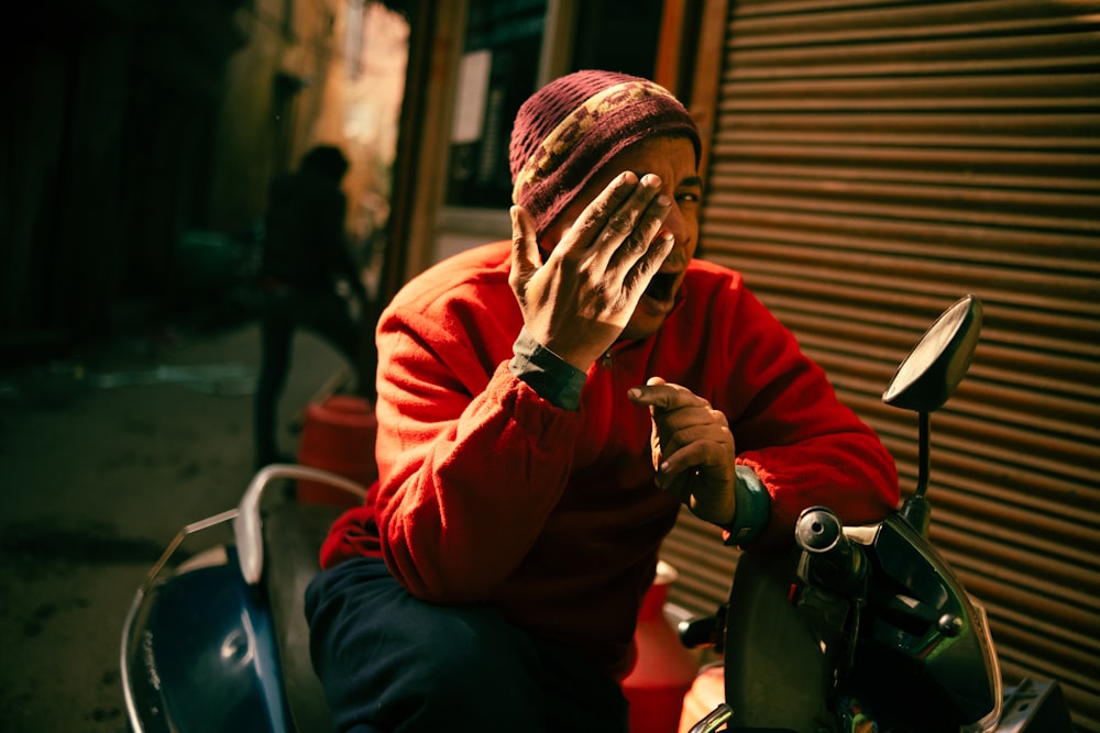 a woman covering her face while sitting on a motorcycle