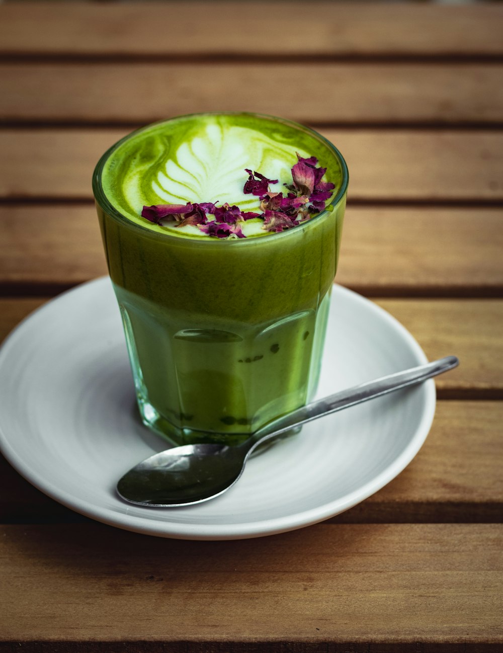 a green drink with a spoon on a plate