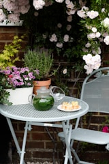 a table and chairs with flowers in the background