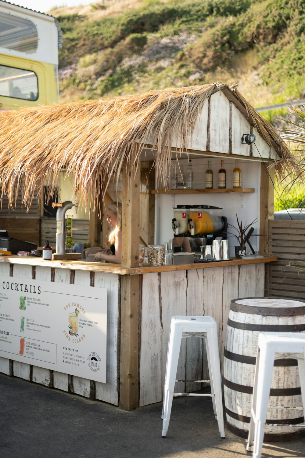 a small bar with a thatched roof and stools