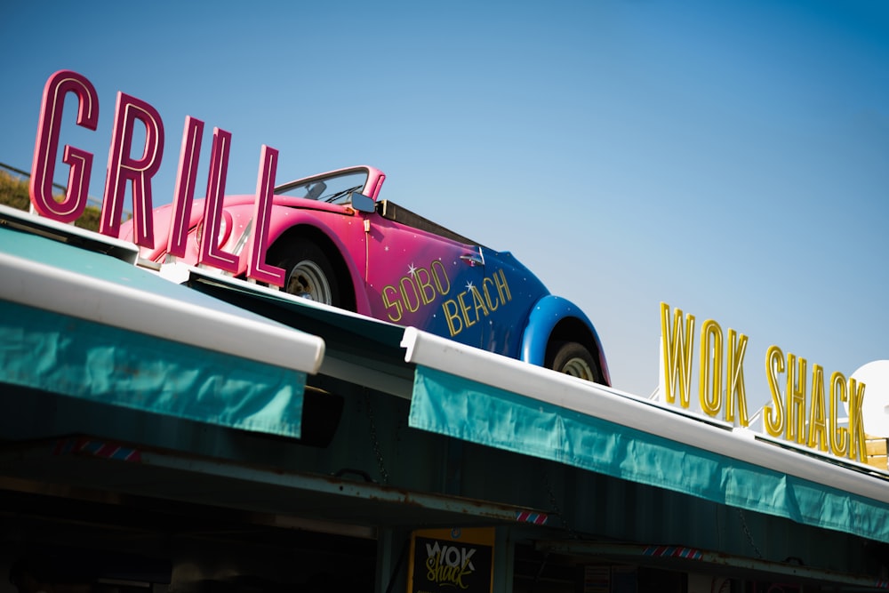 a pink car is parked on top of a restaurant