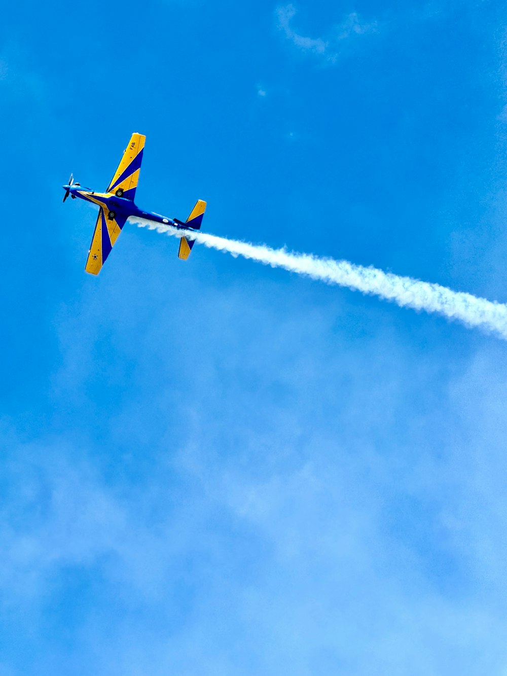 Ein blau-gelbes Flugzeug fliegt am Himmel