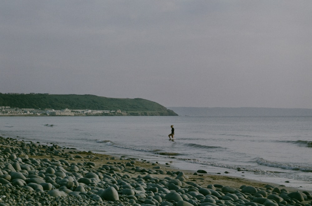 a person standing on a rocky beach next to the ocean