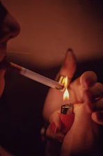 a woman lighting a cigarette with a lighter in her hand