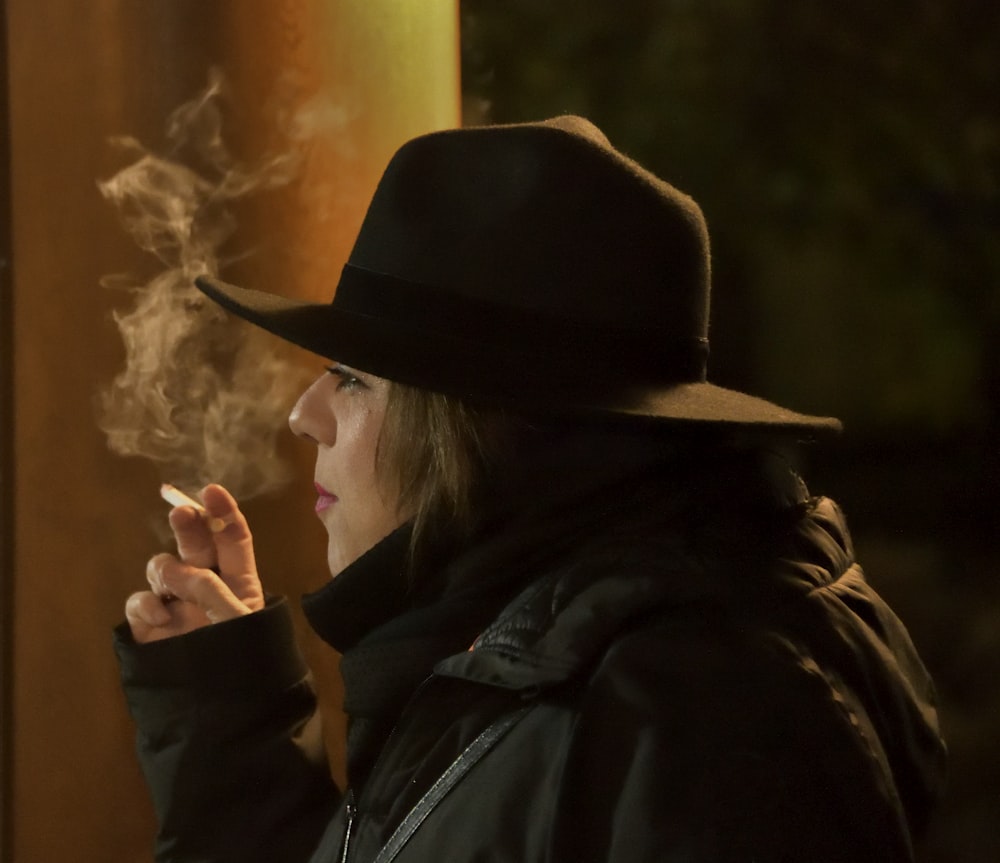 a woman in a hat smoking a cigarette