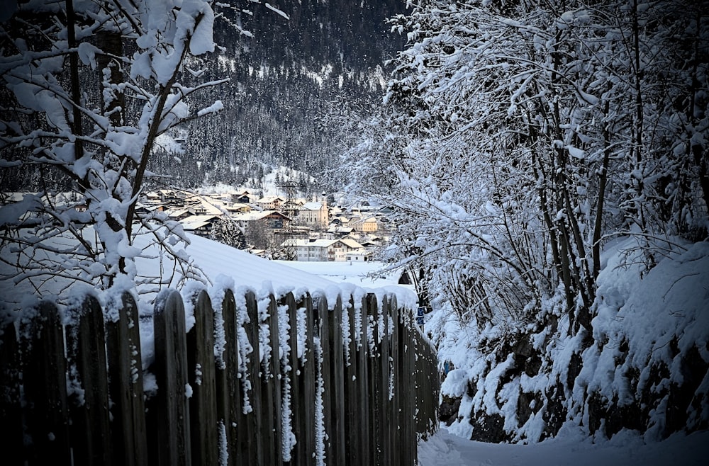 a fence is covered in snow near a village