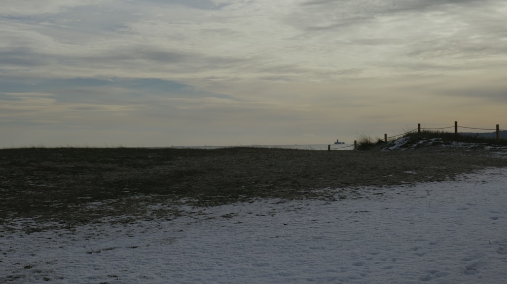 a beach covered in snow next to a fence