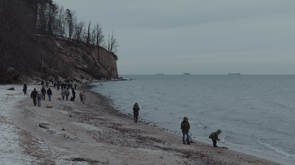 a group of people walking along a beach next to the ocean