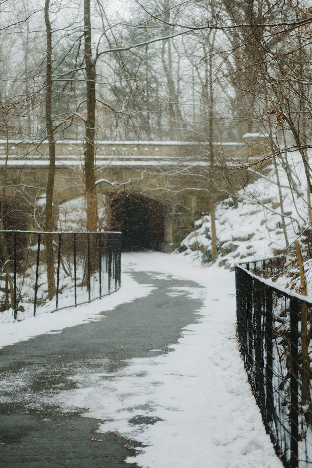 a snow covered path with a bridge in the background