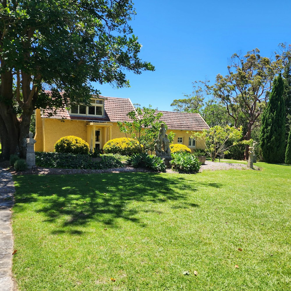 a yellow house in the middle of a lush green yard